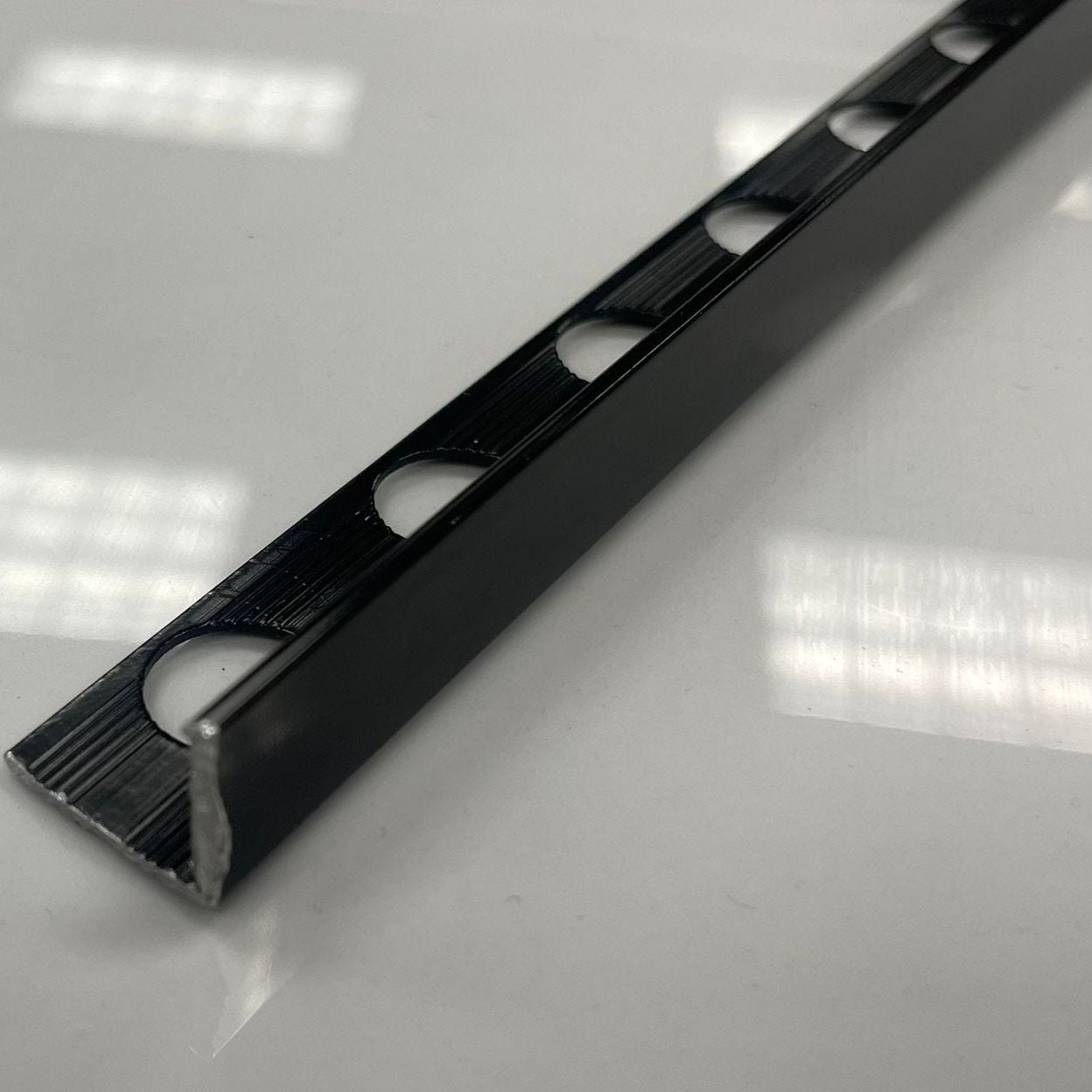 Black coloured aluminum tile moulding/trim with a 1/2" thickness.