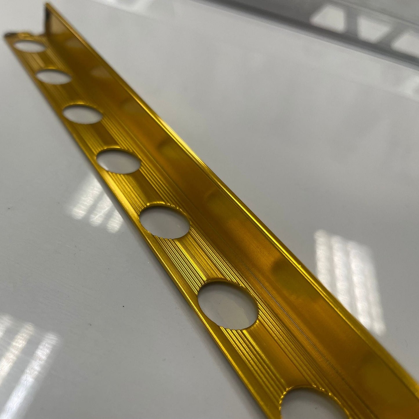Gold/brass coloured polished aluminum tile moulding/trim with a 1/2" thickness.