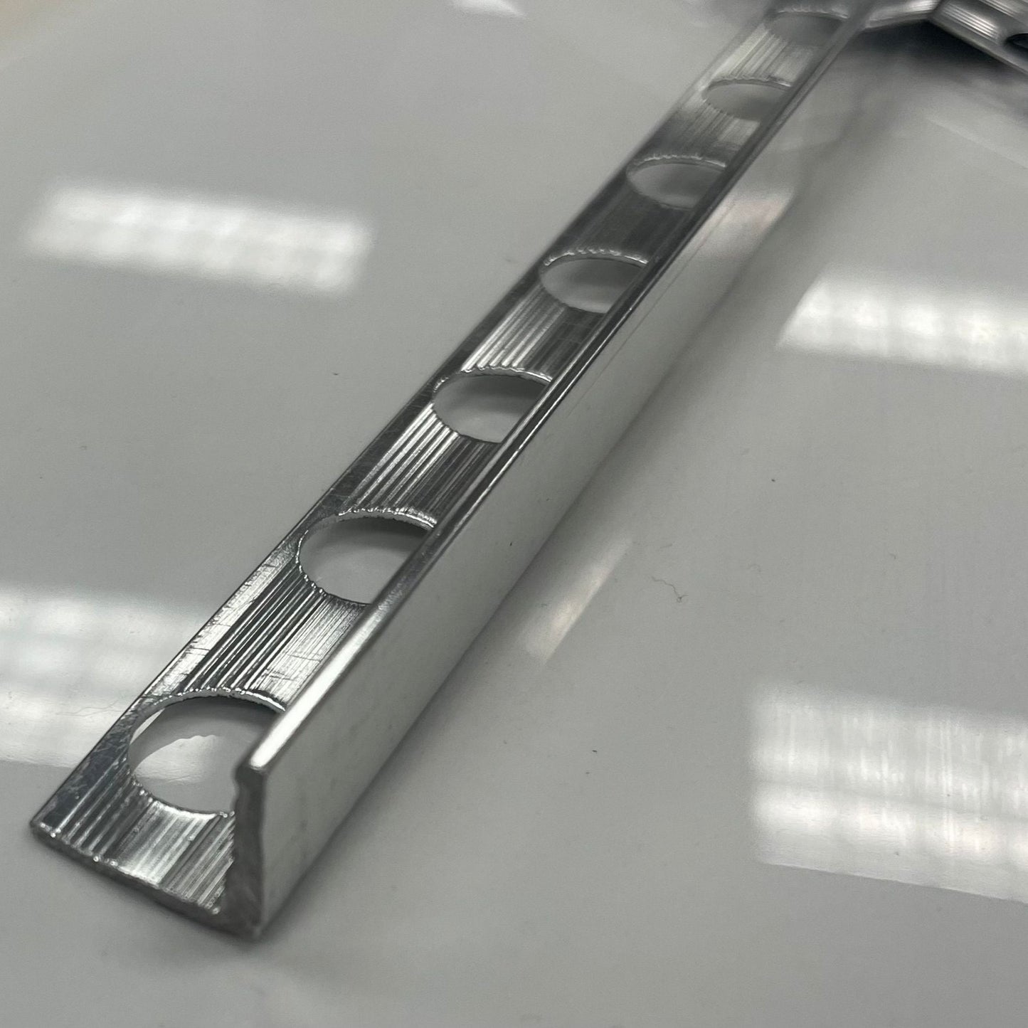 Chrome coloured polished aluminum tile moulding/trim with a 1/2" or 3/8" thickness.