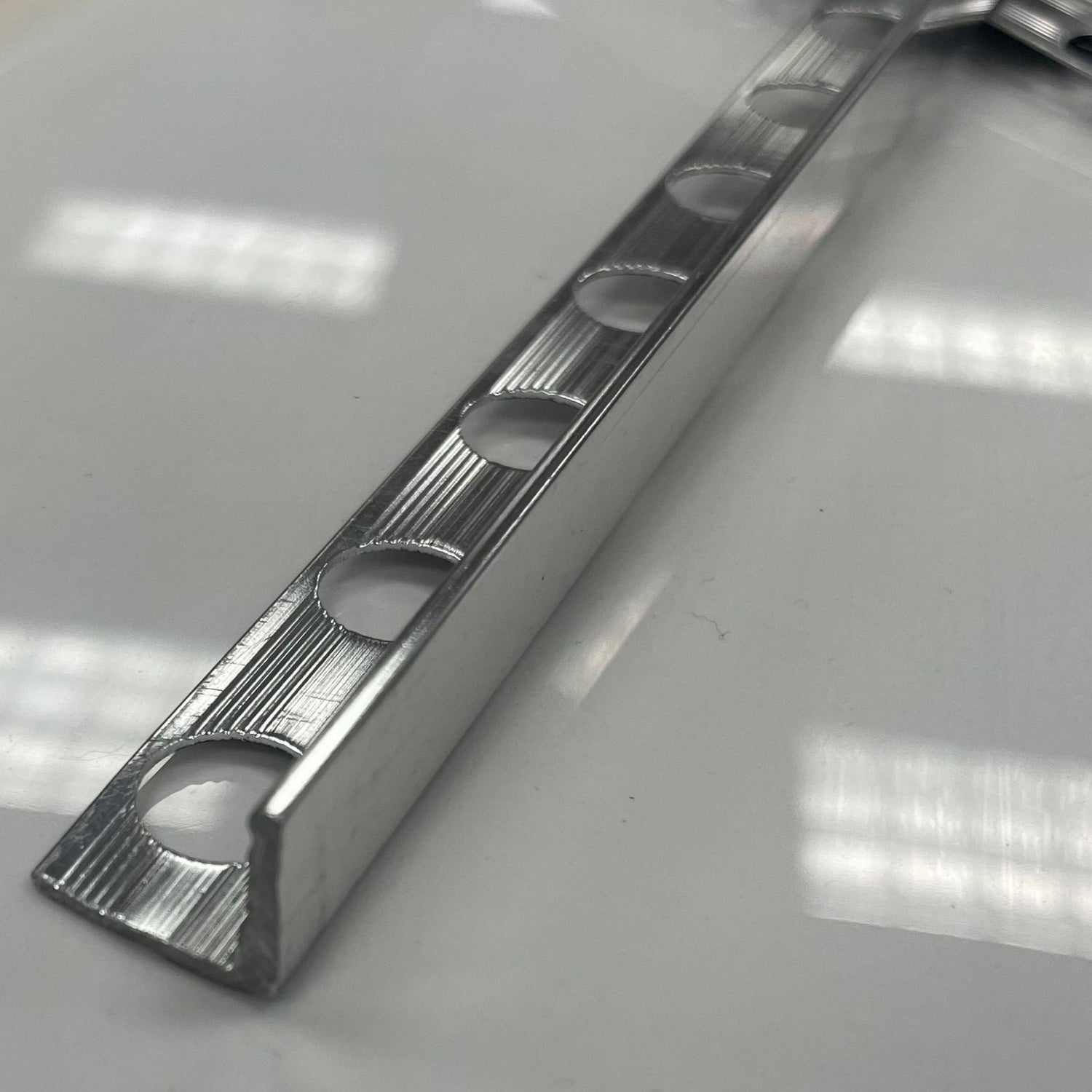 Chrome coloured polished aluminum tile moulding/trim with a 1/2" or 3/8" thickness.
