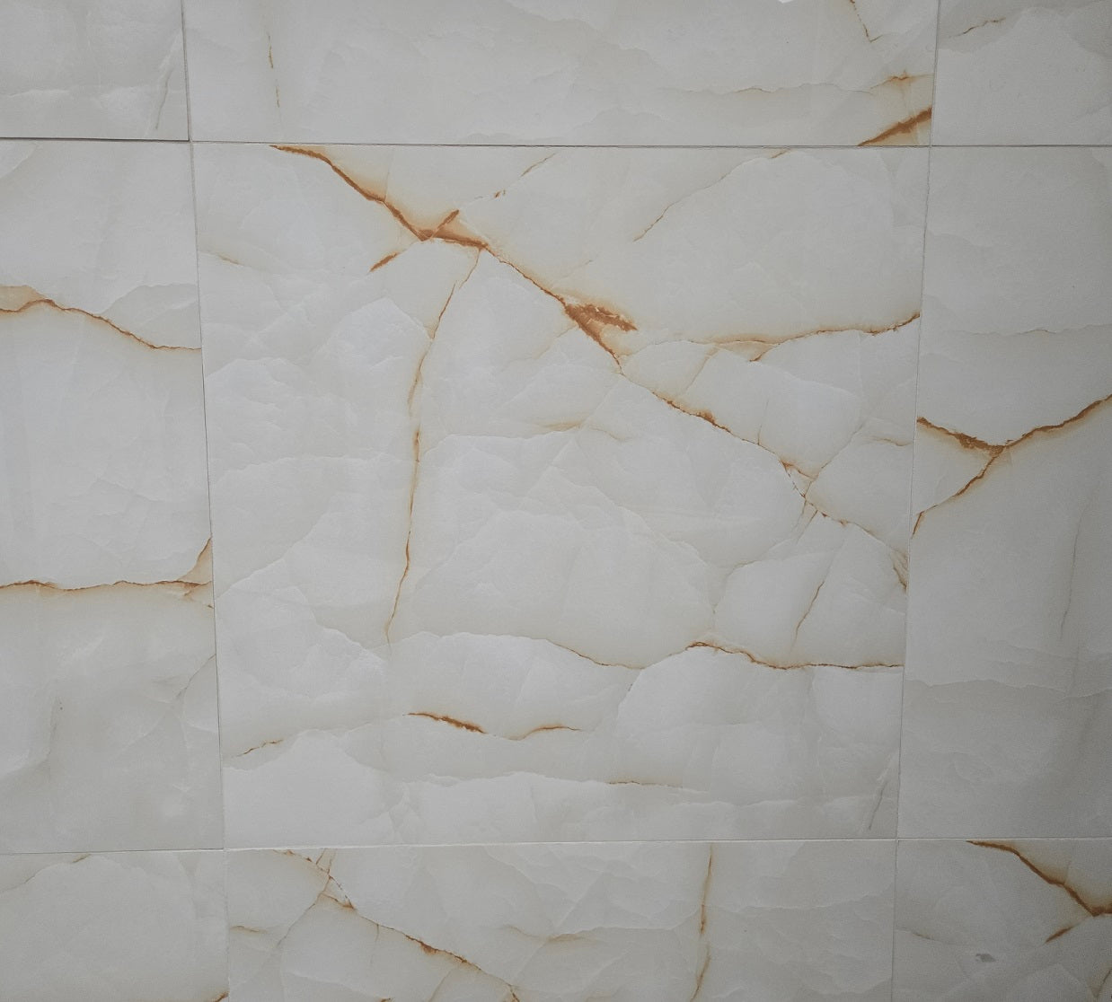 Aurora Gold polished porcelain tile with a white and gold marble onyx design, for floors and walls. In a 24x24" size.