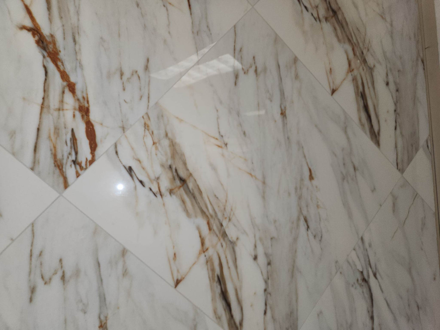Calacata glossy ceramic tile with a white and gold marble style, for floors and walls. In a 23x23" size.