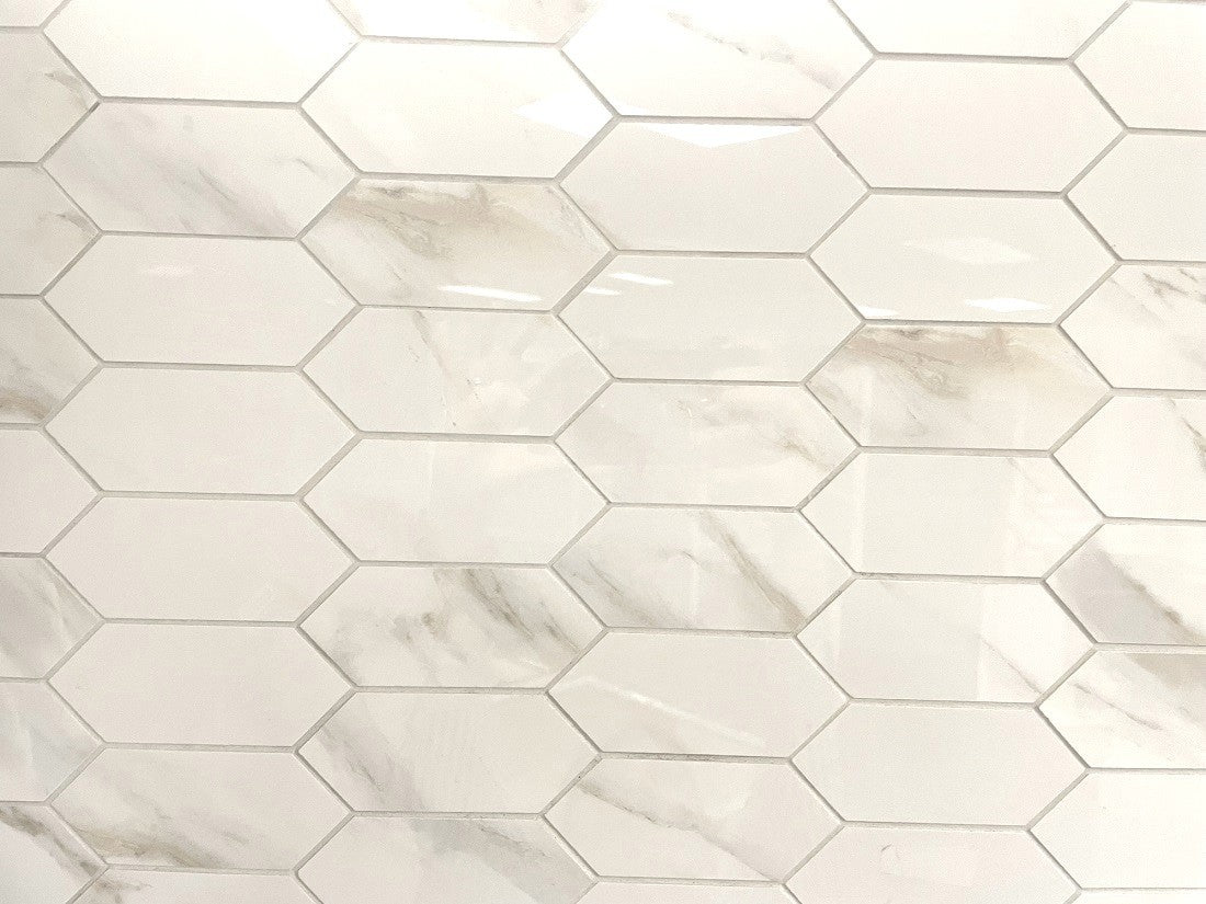 Calacatta Oro porcelain tile with a white/gold marble design, for floors and walls. In an elongated hexagon mosaic.