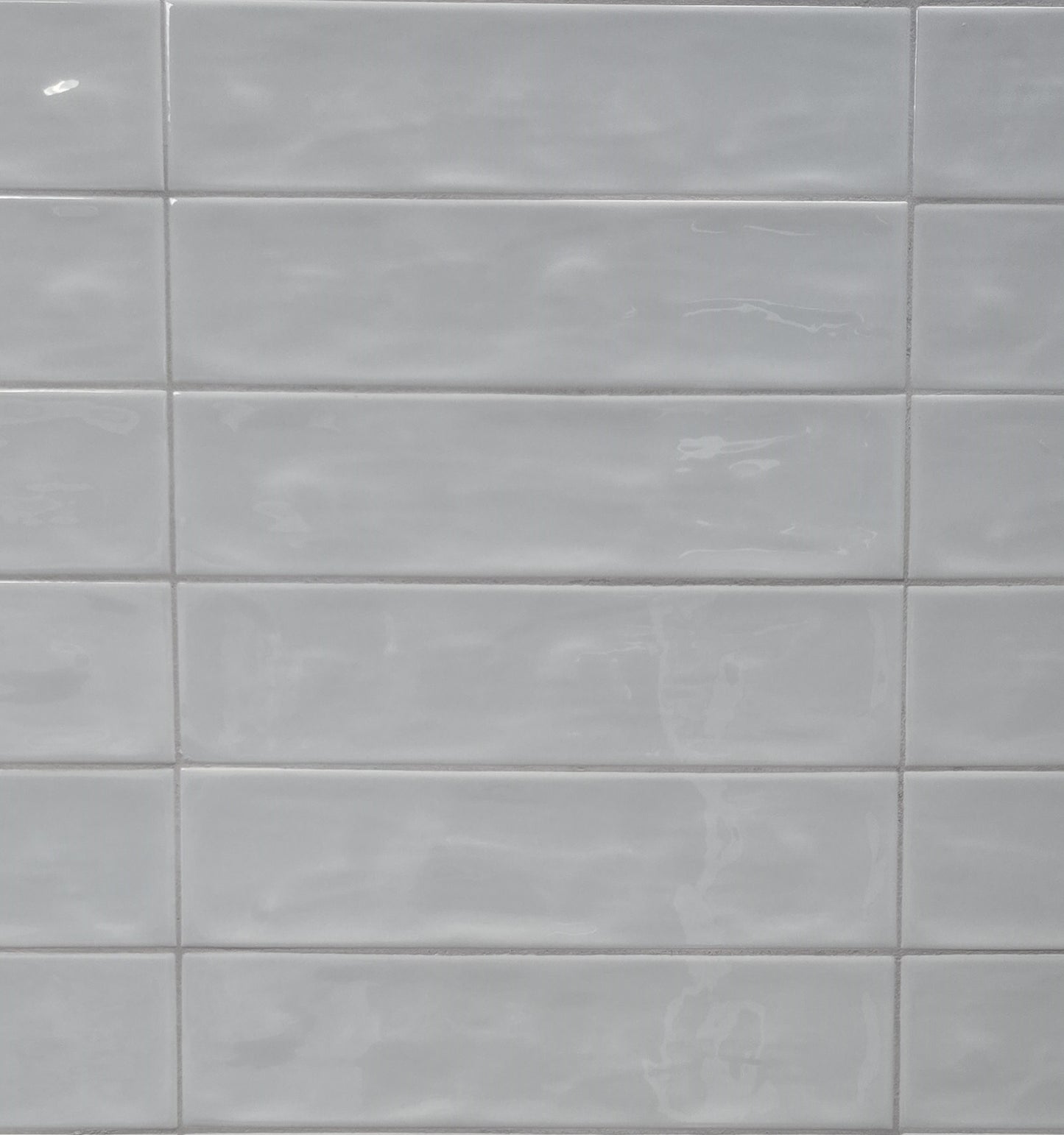 Dazzle Smoke glossy ceramic subway tile with a light blue wavy artisan style for walls. In a 3x12" size.