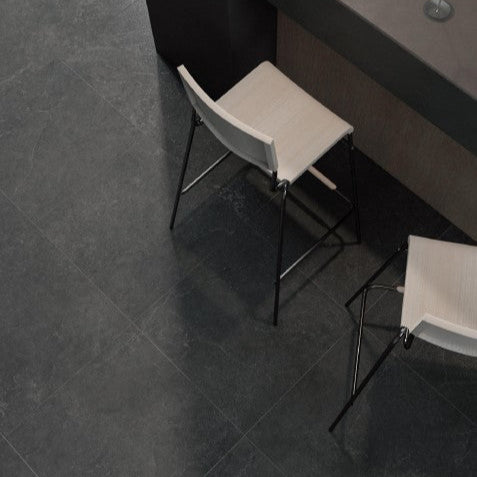 Lithos Stone Charcoal matte porcelain tile with a black stone design, for floors and walls. Installed in a room.