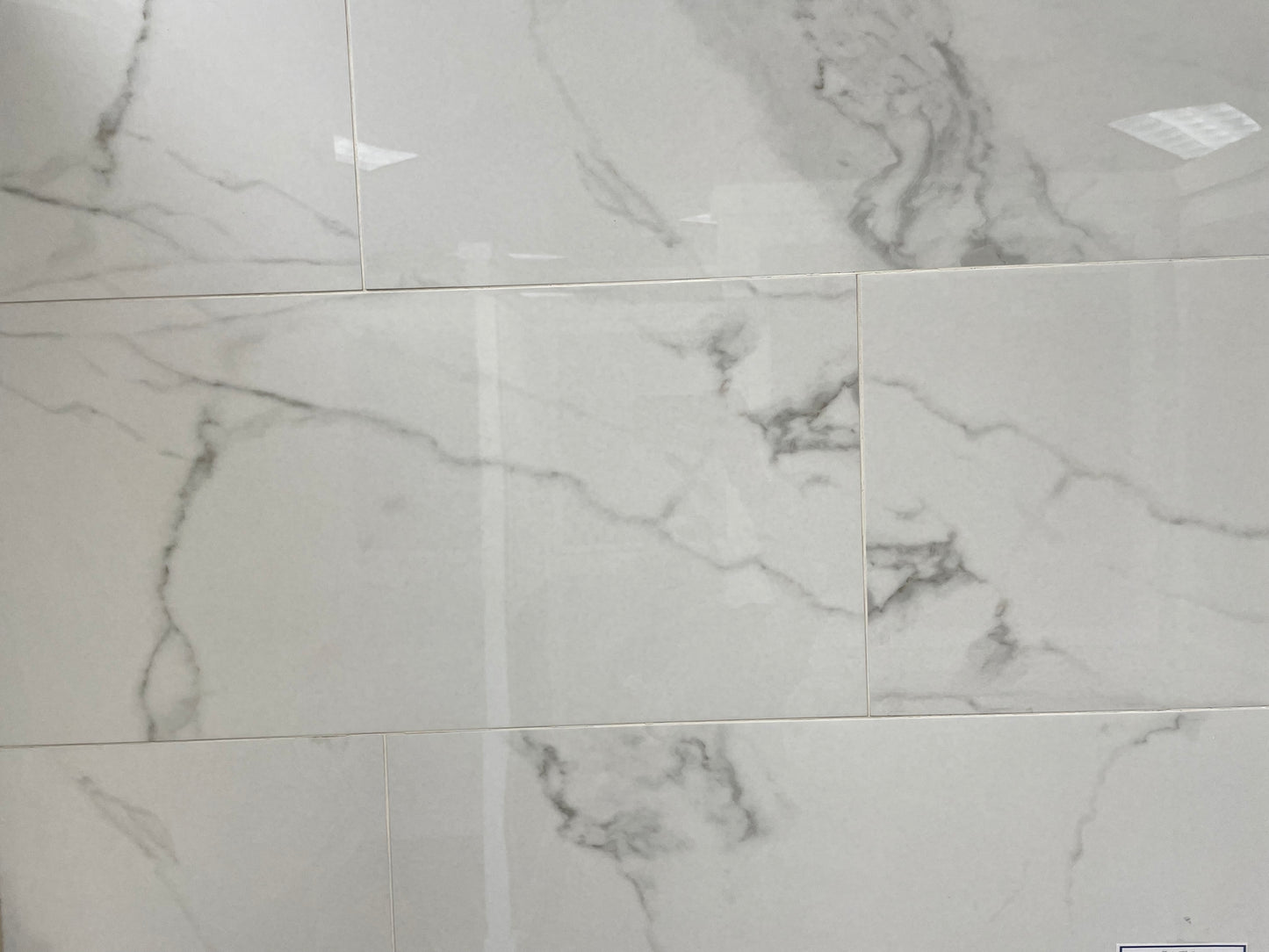 Carrara Bianco polished porcelain tile with a white marble design, for floors and walls. In a 14x28" size.
