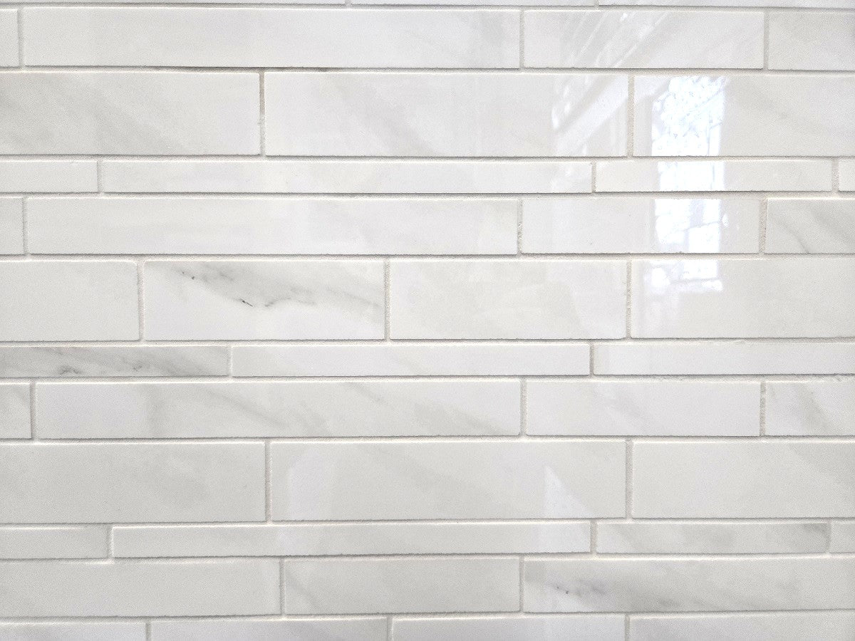 Marmo Isabella polished porcelain tile in a soft white marble style. In a random strip mosaic size.