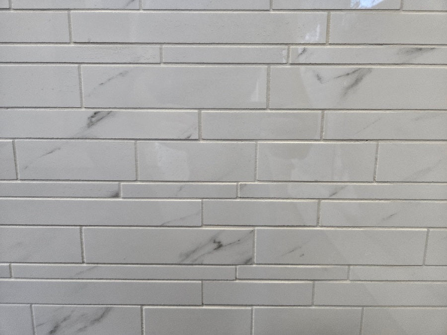 Marmo Julieta polished/matte porcelain tile in a soft white marble style. In a random strip mosaic size.