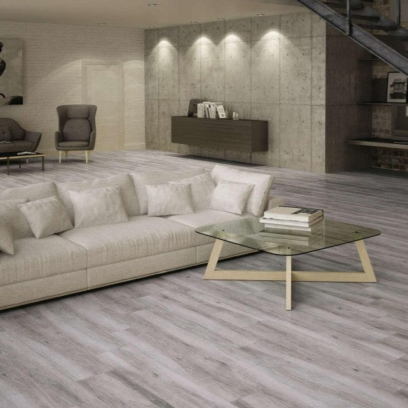 Pecan Gris matte porcelain tile with a grey wood design, for floors and walls. Made in Spain, installed in a room.