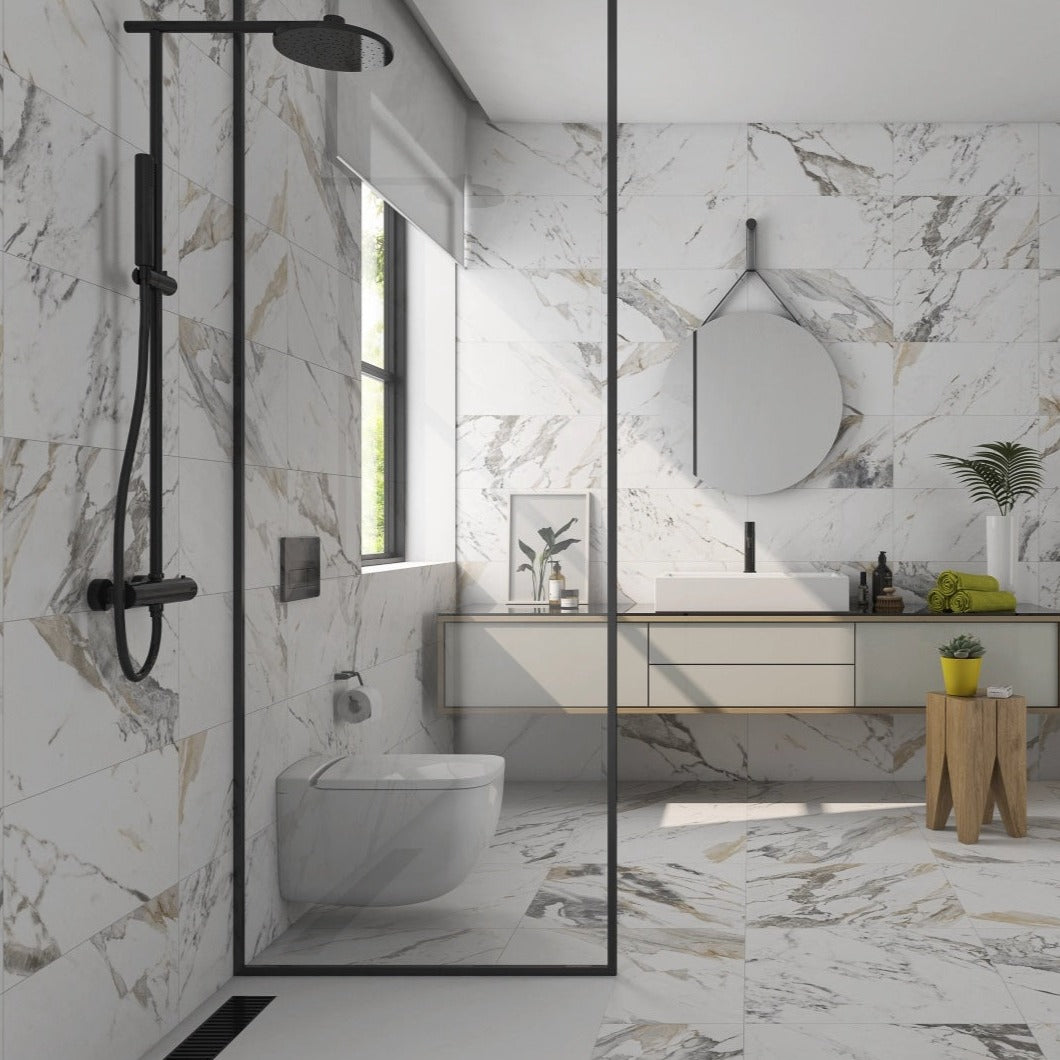 Tinenza porcelain tile with a white, gold, and silver marble design, for floors and walls. Installed in a bathroom.