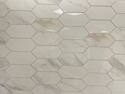 Calacatta Oro porcelain tile with a white/gold marble design, for floors and walls. In an elongated hexagon mosaic.