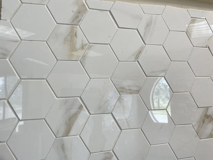 Calacatta Oro polished porcelain tile with a white/gold marble design, for floors and walls. In a large hexagon mosaic.