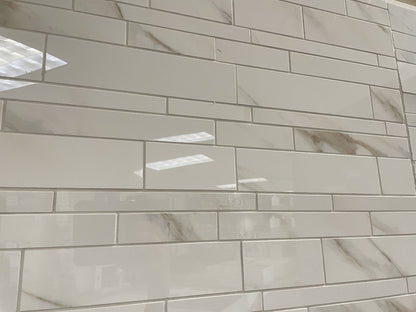 Calacatta Oro polished porcelain tile with a white/gold marble design, for floors and walls. In a random strip mosaic.