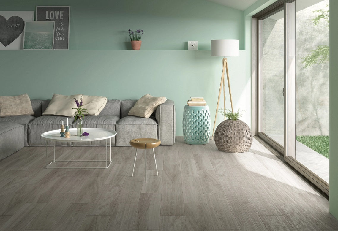 Corsica Argento matte ceramic tile with a grey wood design, for floors and walls. Made in Spain, installed in a room.
