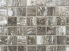 Ferrara Noce polished porcelain tile with a brown stone design, for floors and walls. In a 1x1" square mosaic size.