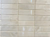 Lazio Ivory polished porcelain tile with a stone design, for floors and walls. In a 1x3" mosaic size.