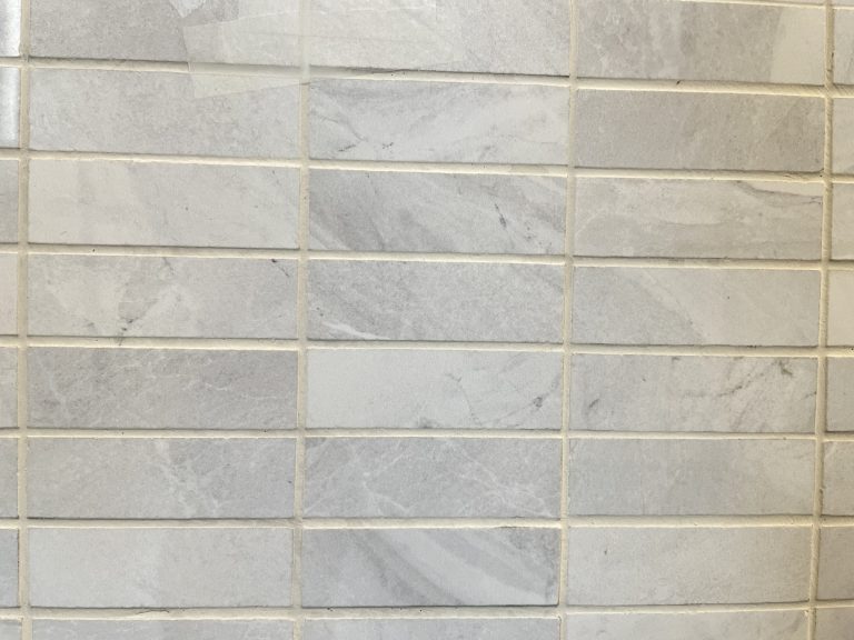 Lazio Pearl polished porcelain tile with a grey stone design, for floors and walls. In a 1x3" mosaic size.