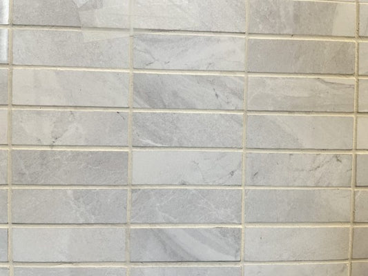 Lazio Pearl polished porcelain tile with a grey stone design, for floors and walls. In a 1x3" mosaic size.