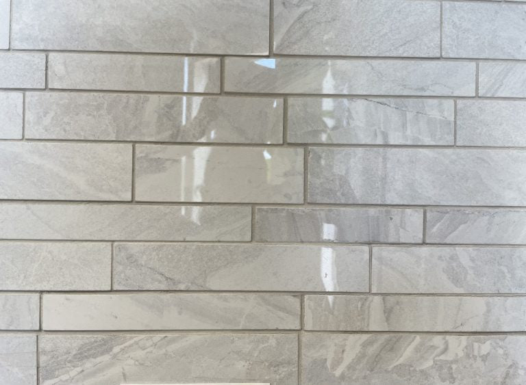 Lazio Pearl polished porcelain tile with a grey stone design, for floors and walls. In a random strip mosaic size.