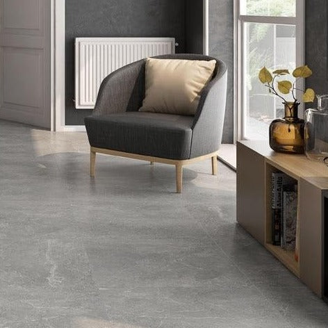 Kibal Gris glossy porcelain tile with a grey stone design, for floors and walls. Made in Spain, installed in a room.