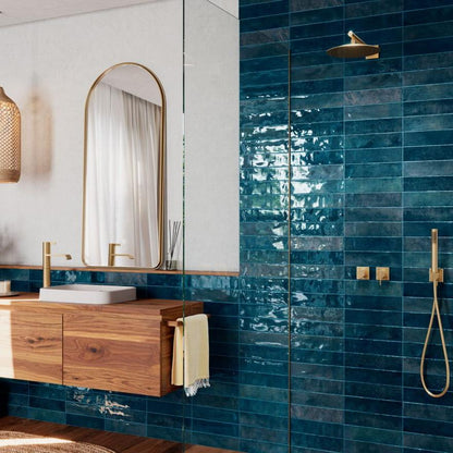 Nairobi Blue artisan style glossy ceramic subway tile with non-flat edge and surface. Installed on a bathroom wall.