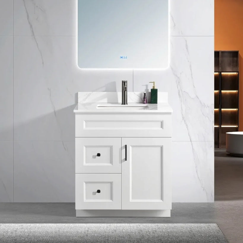 30 inch wood bathroom vanity in a white colour with a carrara quartz top and black hardware. With a door and drawers.
